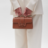 Plant Based Vegan Luxury Sustainable Handbag Made in Spain Ubrique Ethical plant-based leather vegan leather savette symmetry pochette clutch top handle cognac tan brown contrast stitching brown small bag chic classy vegan luxury bags ethical luxury quiet luxury plastic-free leather best british handbag brands mid range handbags 
