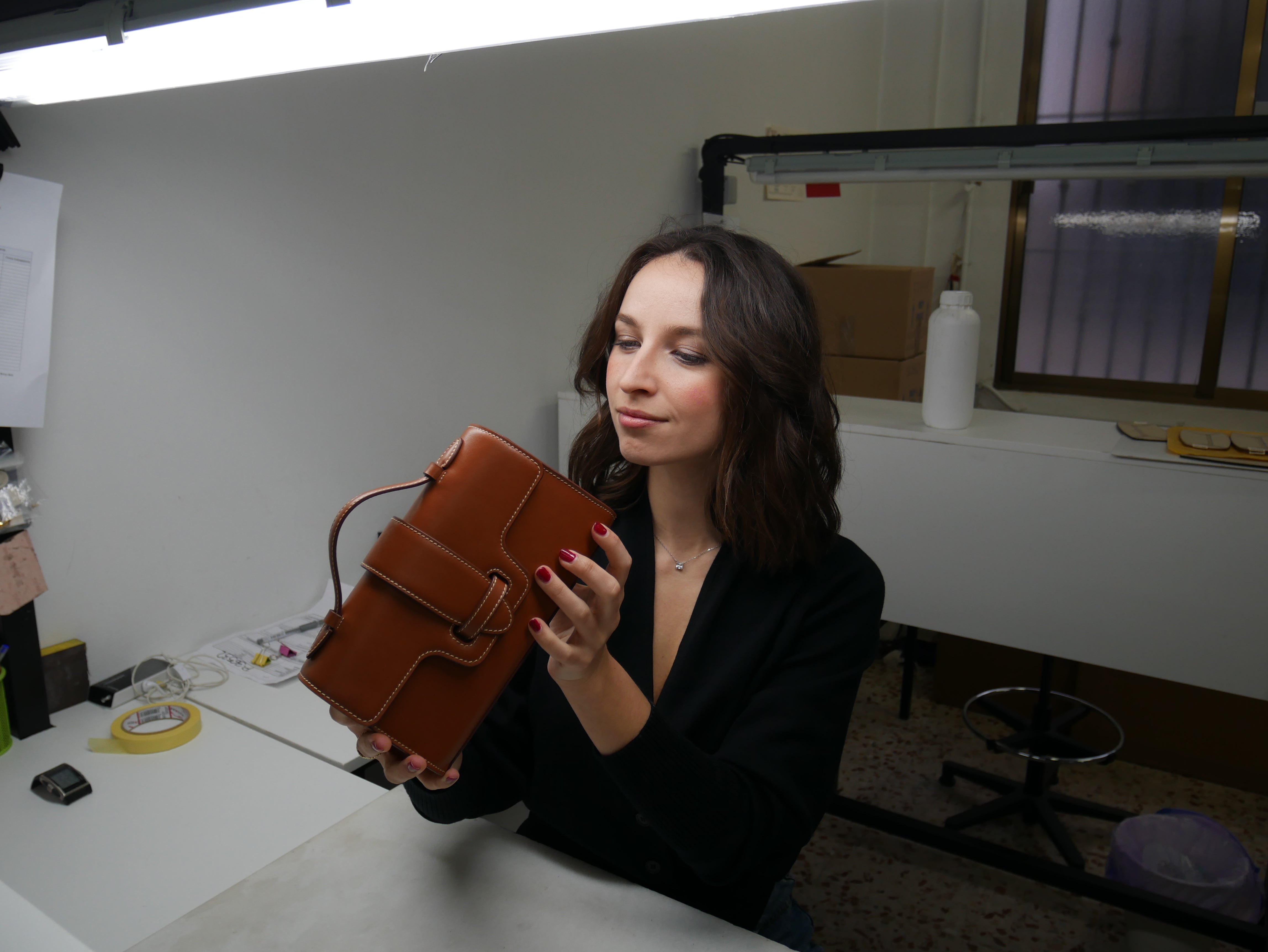 Woman holding a brown leather bag in an indoor setting